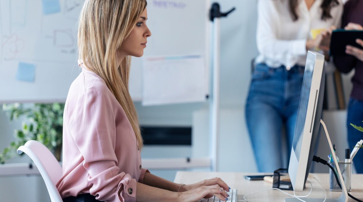 Beautiful young business woman working with computer while sitting in desk in modern startup office.